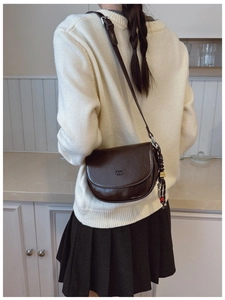 Détail du sac besace en cuir marron foncé avec logo embossé COIN 2DN et breloque