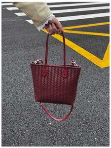 Détail de la texture en cuir tressé d'un sac cabas bordeaux avec bandoulière