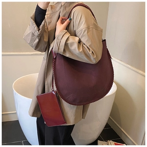 Detail of burgundy leather crescent shoulder bag with woven stitching and coin purse