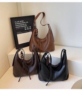 Detail of vintage textured leather tote bags with wooden bead tassels in three colors