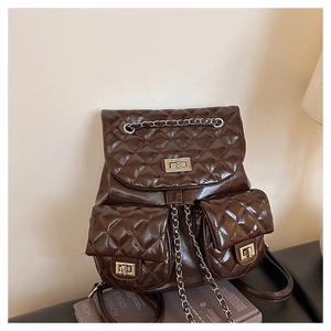 Close-up of quilted gloss leather texture and silver metal twist locks on dark brown backpack