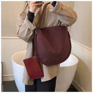 Detail of burgundy half-moon shoulder bag with woven edge and matching small zipper pouch