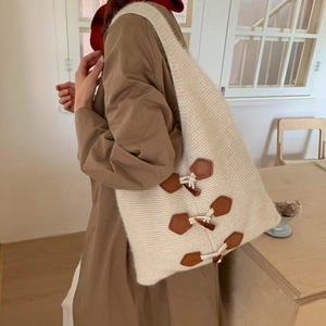 Detail view of cream knitted tote bag featuring vintage brown toggle leather closures