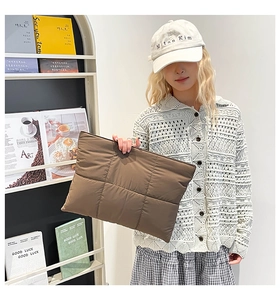 Detail of a dark brown quilted laptop sleeve with oversized puffer grid pattern textures