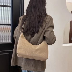 Detail of hobo bag showing matte texture and stitching on brown herringbone blazer