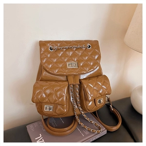 Detail of caramel quilted backpack featuring silver twist locks and chain strap texture