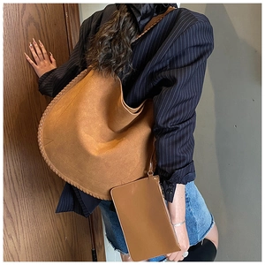 Detail of a brown suede hobo bag featuring decorative woven edges and a matching pouch