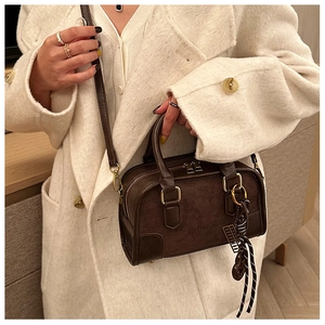 Détail d'un sac Boston vintage marron foncé en daim et cuir porté par un mannequin