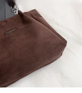 Détail du sac cabas vintage en daim marron avec chaîne métallique et écusson en cuir