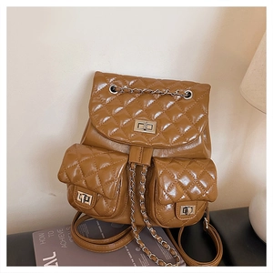 Detail of brown quilted backpack featuring metal twist locks and chain straps