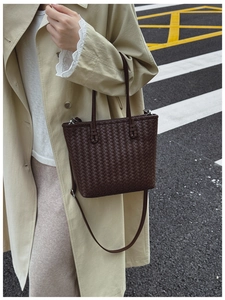 Détail d'un sac cabas tressé marron foncé avec bandoulière réglable porté par un mannequin