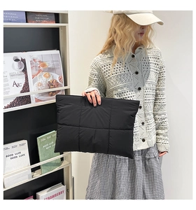 Detail of a black quilted laptop sleeve with soft padded texture held by a model
