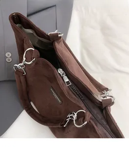 Détail d'un sac cabas en daim café avec fermeture éclair argentée et logo de la marque