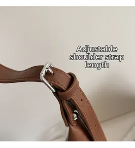 Detail of adjustable brown leather shoulder strap with silver metal buckle on handbag