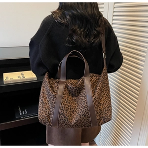 Detail of leopard print tote bag featuring brown leather handles and wide shoulder strap