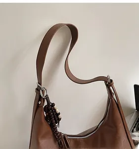 Detailed side view of the brown crescent bag with retro wooden bead charm and texture