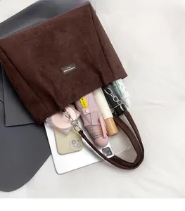 Vue détaillée du sac cabas en daim marron montrant sa grande capacité et son étiquette de marque