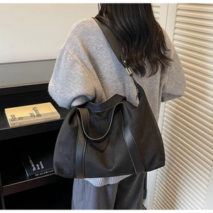 Detail of a large black matte tote bag showing the soft texture and reinforced leather straps