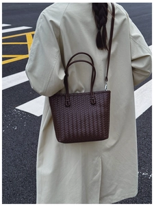 Détail de la texture d'un sac cabas tressé marron foncé sur fond de trench-coat beige