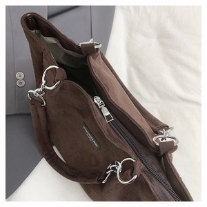 Detail of dark brown suede tote bag featuring silver metal rings and secure black zipper