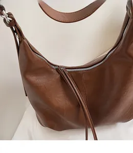Close-up of a smooth metal zipper on a brown vintage hobo bag with textured leather