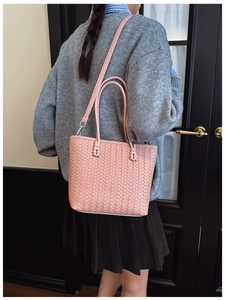 Détail de la texture tressée du sac seau rose montrant l'artisanat en cuir synthétique