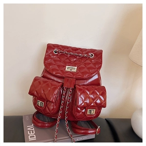 Detailed view of red quilted backpack featuring silver chain straps and metal twist locks