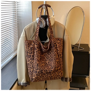 Detail of a large leopard print tote bag with plush texture hanging in a cozy room