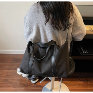 Detail of a black large-capacity tote bag with adjustable strap in minimalist room