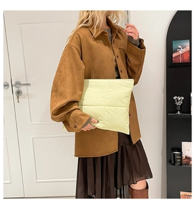 Detail showing a light yellow puffer clutch bag paired with a brown suede shirt jacket