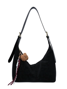 Minimalist black suede hobo bag with teddy bear charm and striped cord on white background