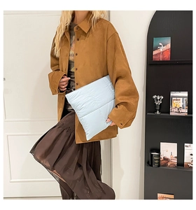 Chic light blue quilted puffer clutch bag paired with a stylish brown suede-like jacket