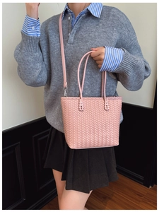 Détail de la texture en cuir tressé rose et des poignées d'un sac seau polyvalent