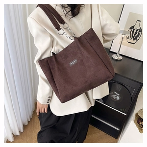 Détail d'un sac cabas en velours côtelé marron avec chaîne argentée et étiquette tissée