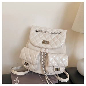 Detail of quilted creamy backpack showing silver metal twist locks and chain straps