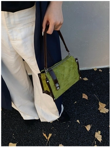 Detail of green suede crossbody bag with rhombus quilting and silver stud accents