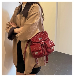 Detail view of burgundy quilted leather backpack with silver metallic turn-lock fasteners