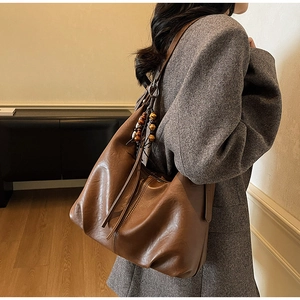 Detail view of the deep brown vintage leather tote bag with stylish beaded long fringe