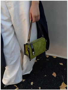 Detail of green suede handbag with beige lattice stitching and brown leather trim