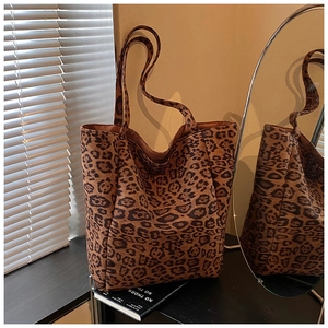 Detailed macro view of large leopard print tote bag with plush texture and side strap