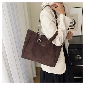 Detail of dark brown suede tote bag featuring a metal chain strap and wide shoulder strap