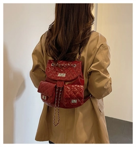 Detail of red quilted faux leather backpack with metallic turn-lock and chain straps