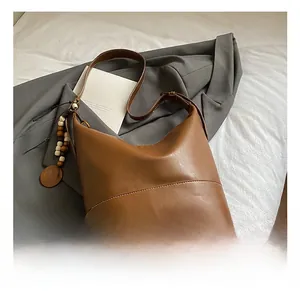 Detailed macro view of brown vintage bucket bag with wooden beads and white stitching