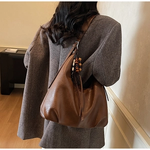 Brown vintage hobo bag with fringe wood beads worn by a model in a grey blazer