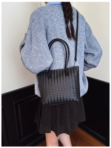 Détail du tissage et de la bandoulière amovible sur le sac seau en cuir noir