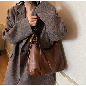 Detail of vintage brown leather hobo bag with unique wooden bead charm decoration