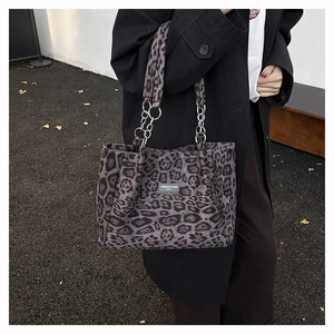 Detail of trendy leopard print tote bag featuring dual metal chains and logo patch