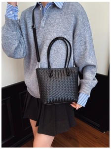 Détail d'un sac cabas noir tissé porté à l'épaule avec une bandoulière réglable