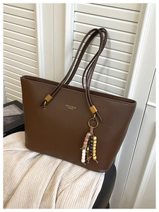 Detailed shot of brown leather tote bag with wooden bead tassel and gold hardware