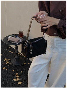 Detail of a vintage cylinder bag with black suede, brown leather trim, and silver buckle